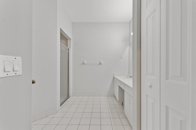 bathroom featuring vanity, tile patterned floors, baseboards, and a stall shower