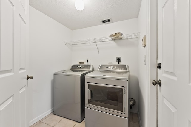 laundry room with visible vents, washer and dryer, a textured ceiling, light tile patterned flooring, and laundry area