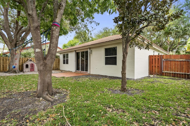 rear view of property featuring a patio, a yard, a fenced backyard, stucco siding, and a tiled roof