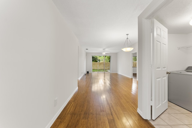 hallway featuring washer / clothes dryer, light wood-type flooring, and baseboards