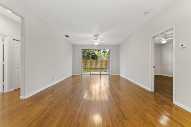 unfurnished room with visible vents, wood finished floors, baseboards, and ceiling fan