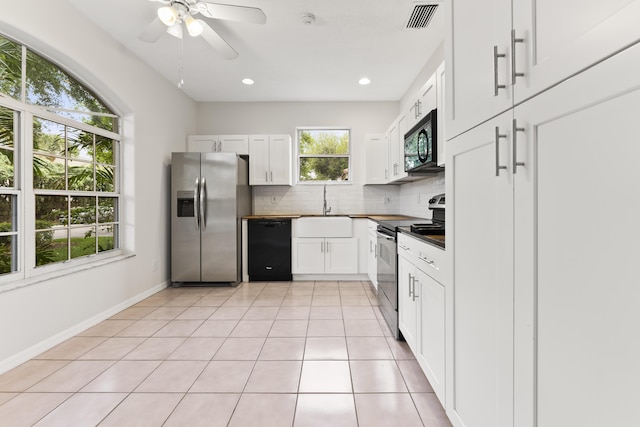 kitchen featuring visible vents, black appliances, backsplash, white cabinetry, and light tile patterned floors