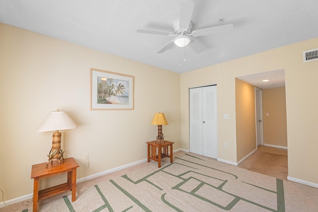 sitting room featuring light colored carpet, a ceiling fan, visible vents, and baseboards