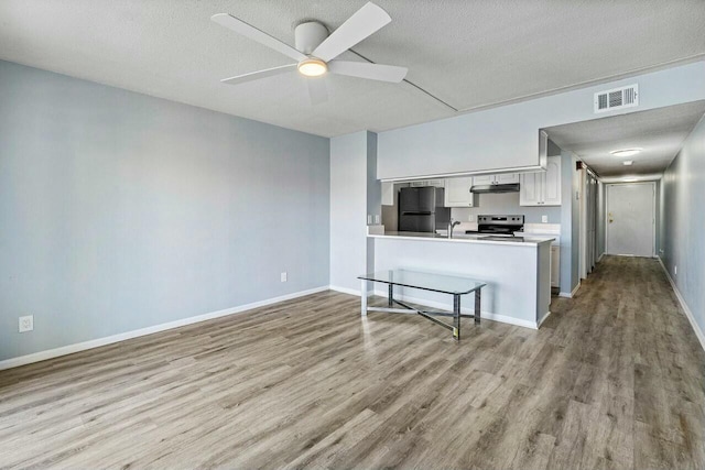 kitchen with stainless steel electric range oven, visible vents, freestanding refrigerator, under cabinet range hood, and white cabinetry