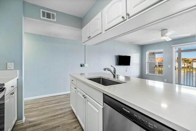 kitchen with visible vents, a sink, stainless steel dishwasher, white cabinets, and light wood finished floors