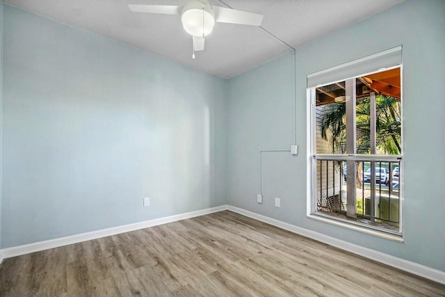 spare room featuring baseboards, wood finished floors, and a ceiling fan