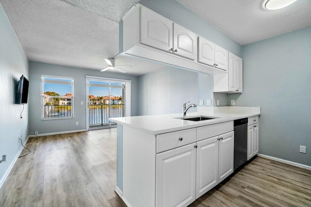 kitchen with light wood finished floors, dishwasher, white cabinetry, a ceiling fan, and a sink