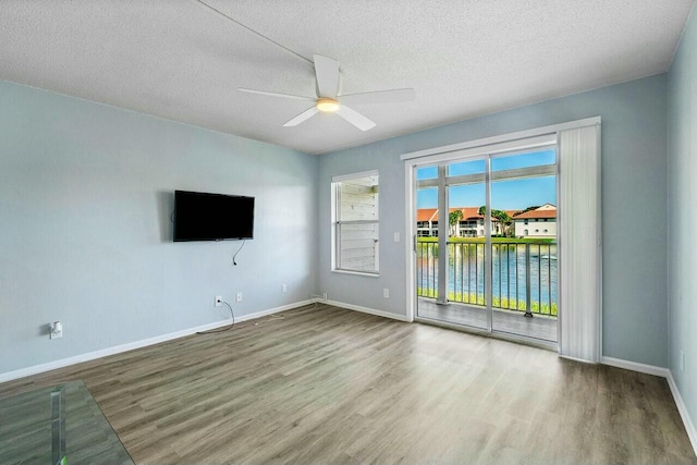 unfurnished living room featuring wood finished floors, a ceiling fan, baseboards, and a textured ceiling