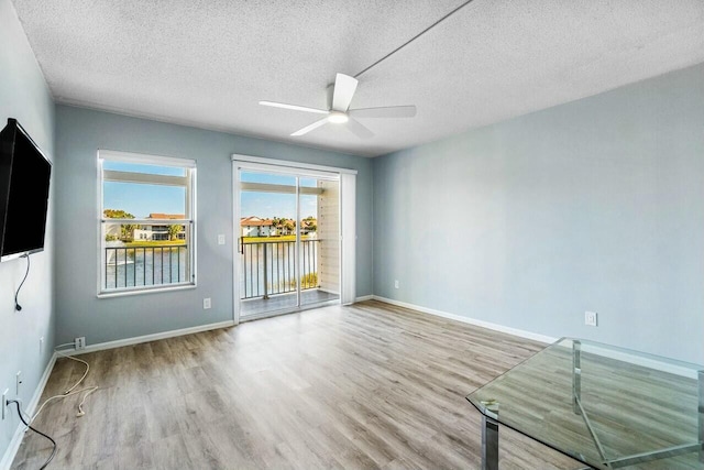 unfurnished room with baseboards, a textured ceiling, wood finished floors, and a ceiling fan