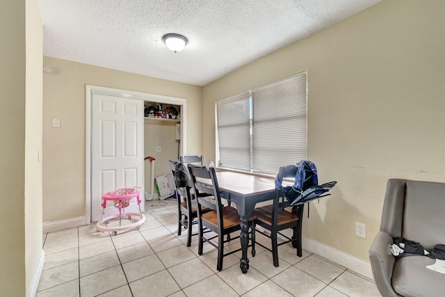 dining space featuring light tile patterned flooring, baseboards, and a textured ceiling