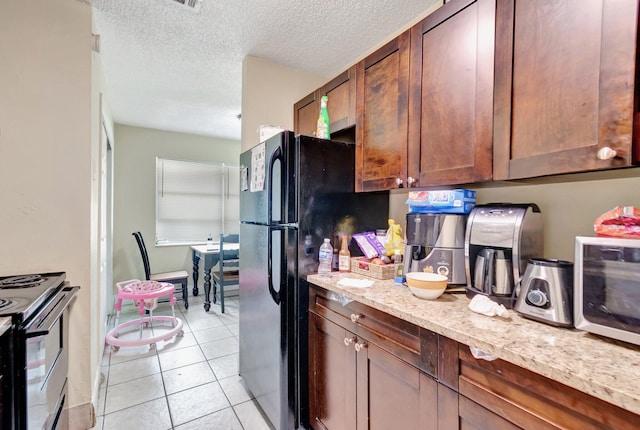 kitchen with black appliances, light tile patterned floors, light stone countertops, and a textured ceiling