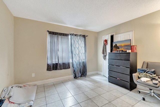 living area featuring light tile patterned flooring, a textured ceiling, and baseboards