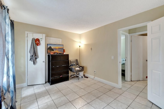 bedroom featuring light tile patterned floors, baseboards, and a textured ceiling