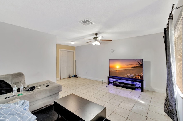 living area featuring visible vents, a ceiling fan, a textured ceiling, light tile patterned floors, and baseboards