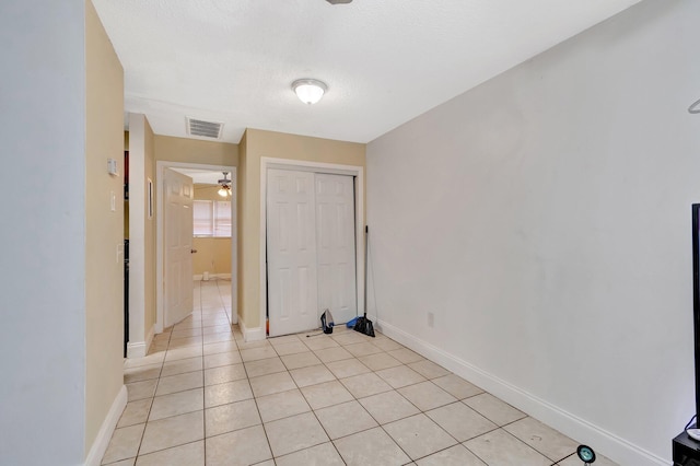 spare room with light tile patterned floors, visible vents, a textured ceiling, and baseboards