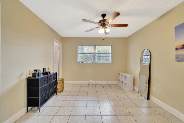 bedroom with light tile patterned flooring, a textured ceiling, a ceiling fan, and baseboards