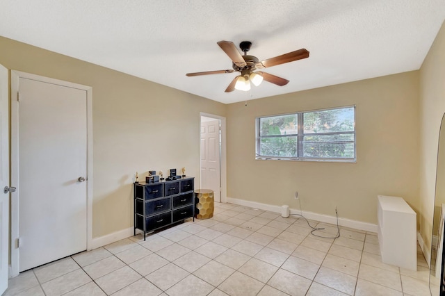 bedroom with baseboards, a textured ceiling, light tile patterned flooring, and a ceiling fan