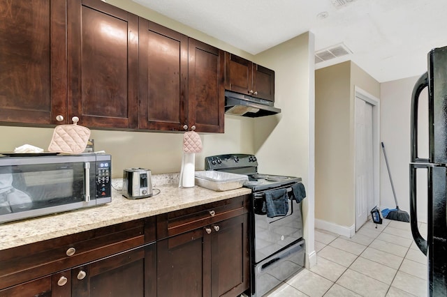 kitchen featuring visible vents, black appliances, under cabinet range hood, light tile patterned flooring, and dark brown cabinets