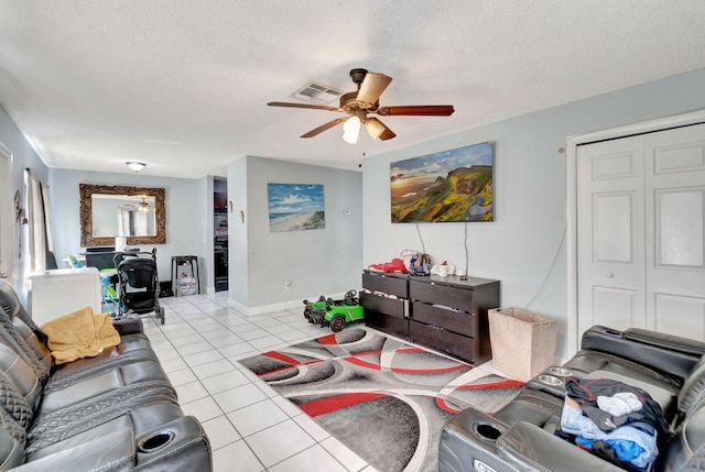 living area featuring visible vents, a ceiling fan, a textured ceiling, light tile patterned flooring, and baseboards