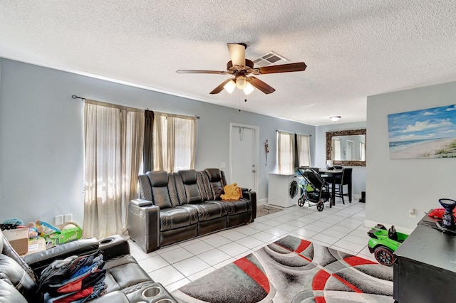 living room featuring light tile patterned floors, a ceiling fan, visible vents, and a wealth of natural light