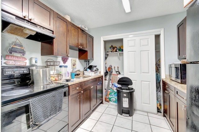 kitchen with black electric range, stainless steel microwave, under cabinet range hood, a textured ceiling, and a sink