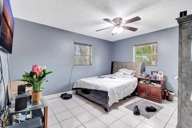 bedroom featuring baseboards, a textured ceiling, light tile patterned flooring, and a ceiling fan