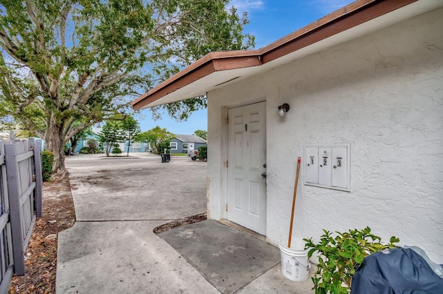 view of exterior entry featuring stucco siding and fence