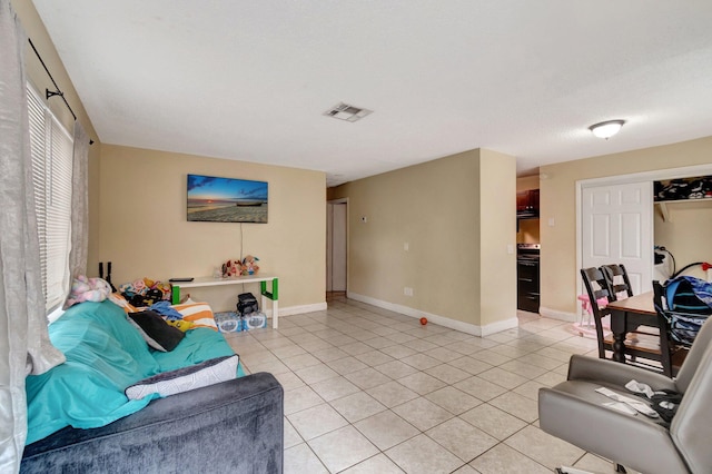 living area with light tile patterned flooring, visible vents, and baseboards