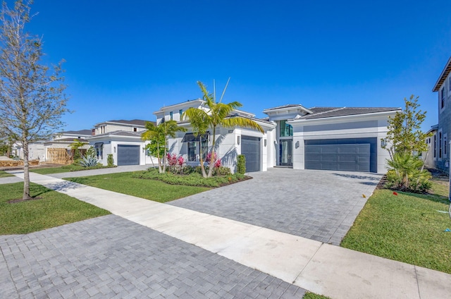 prairie-style house with a front yard, decorative driveway, an attached garage, and stucco siding