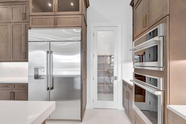 kitchen with light countertops, glass insert cabinets, and appliances with stainless steel finishes