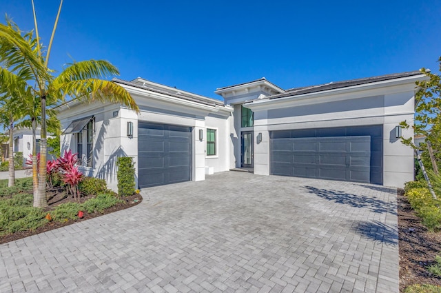 single story home with stucco siding, an attached garage, and decorative driveway