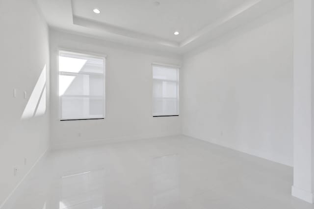 unfurnished room with recessed lighting and a raised ceiling