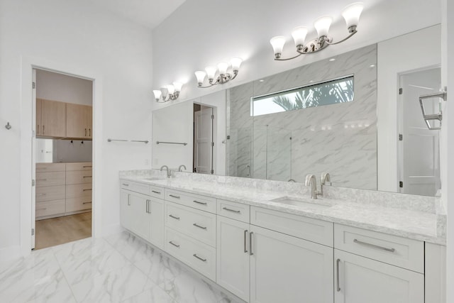 bathroom with a sink, a marble finish shower, marble finish floor, and double vanity