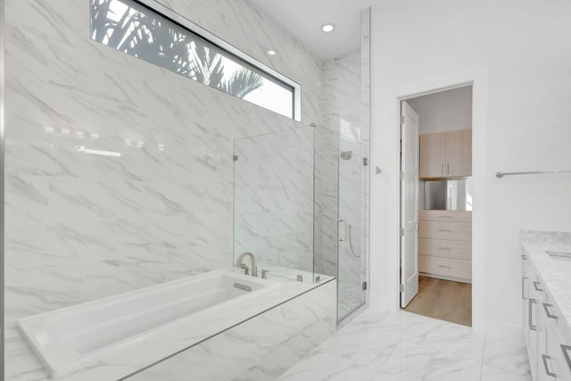 bathroom featuring a garden tub, marble finish floor, recessed lighting, a marble finish shower, and vanity