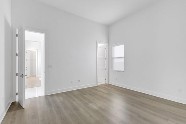 spare room with baseboards and light wood-style floors