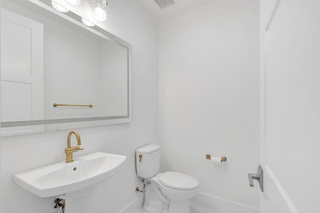 bathroom featuring visible vents, toilet, baseboards, and a sink