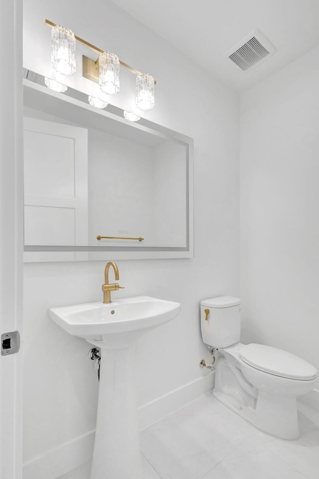 half bathroom with toilet, baseboards, and visible vents