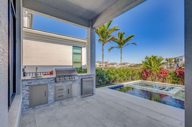 view of patio with grilling area, exterior kitchen, a fenced backyard, and a sink