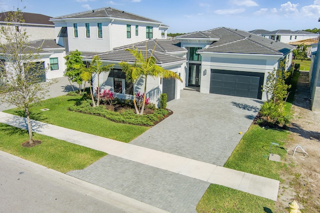 view of front of property with a tiled roof, decorative driveway, a garage, and stucco siding