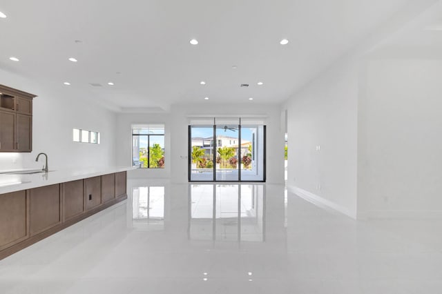 kitchen with baseboards, open floor plan, light countertops, recessed lighting, and a sink