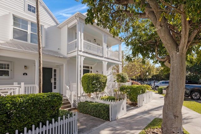 view of home's exterior featuring a porch, a balcony, and a fenced front yard