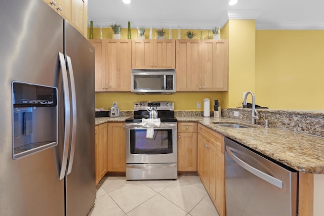 kitchen featuring light stone countertops, light tile patterned floors, appliances with stainless steel finishes, a peninsula, and a sink