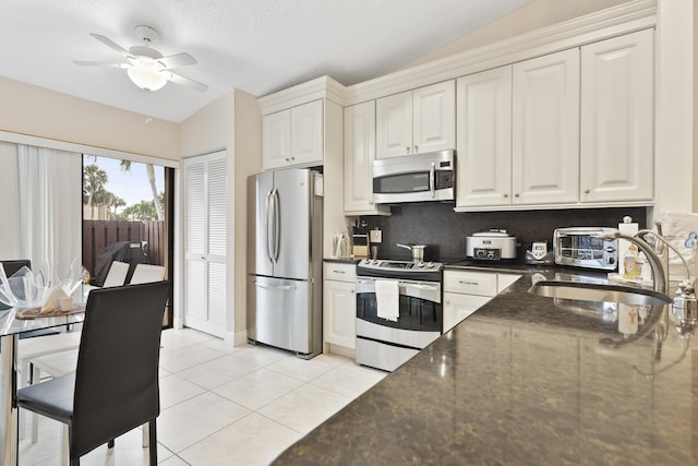 kitchen featuring a ceiling fan, a sink, stainless steel appliances, white cabinets, and light tile patterned floors