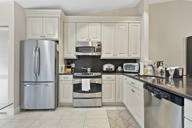 kitchen featuring a sink, appliances with stainless steel finishes, a toaster, light tile patterned floors, and decorative backsplash