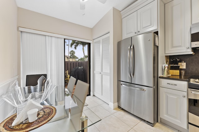 kitchen with light tile patterned floors, backsplash, appliances with stainless steel finishes, and white cabinetry