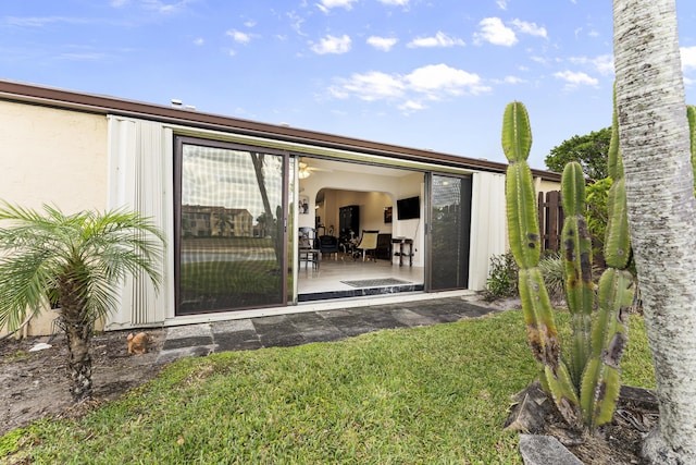 back of property featuring a yard and stucco siding