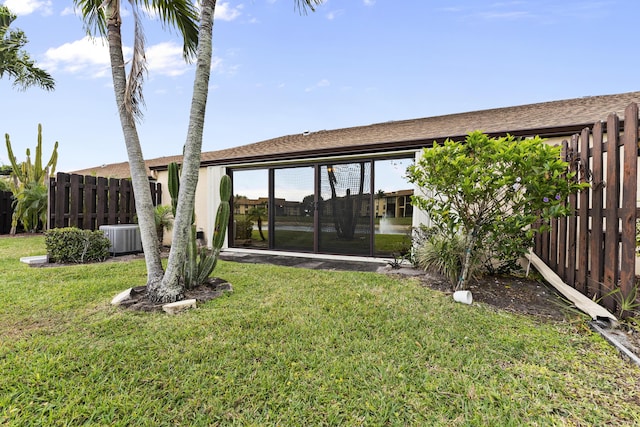 back of property with central AC, a sunroom, a yard, and fence