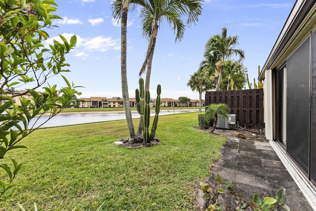 view of yard featuring fence, central AC, and a water view