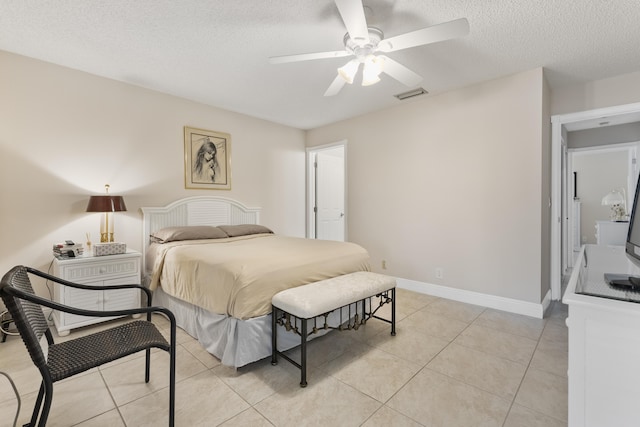 bedroom featuring visible vents, ceiling fan, baseboards, light tile patterned flooring, and a textured ceiling