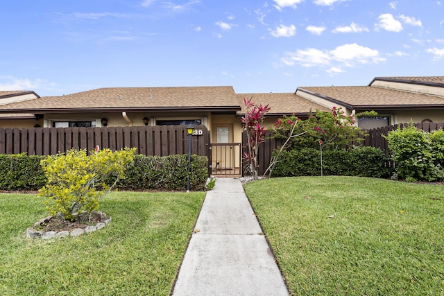 view of front of property with a front lawn, fence, roof with shingles, and stucco siding